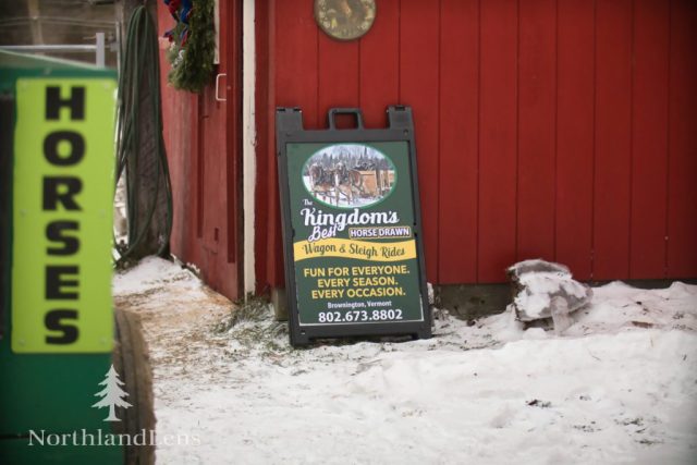 A welcome sign outside the barn marks the entrance to The Kingdom’s Horse Drawn Wagon and Sleigh Rides in Brownington, where guests gather for horse-powered winter adventures on snowy trails. (Photo by Tim Lenahan)