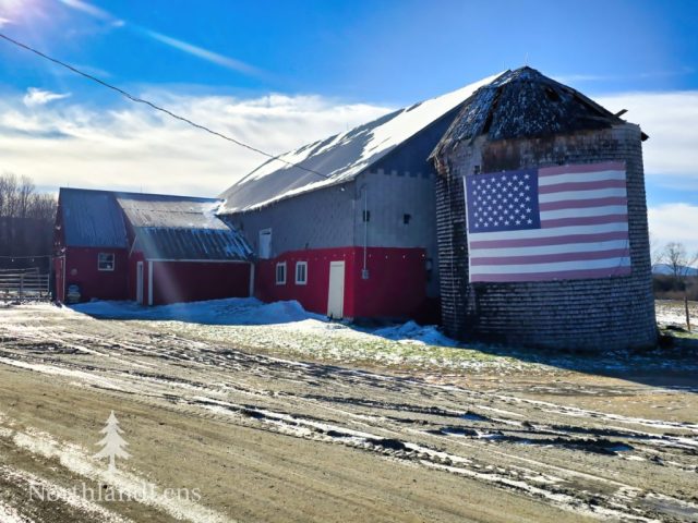 The barn and silo at The Kingdom’s Horse Drawn Wagon and Sleigh Rides stand out against a bright winter morning in Brownington, complete with a weathered American flag welcoming families and travelers alike. (Photo by Tim Lenahan)