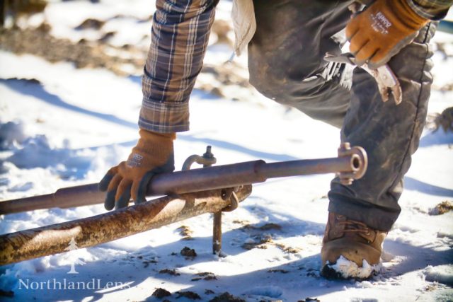 Jeff Simpson checks and adjusts the wagon tongue hardware in the snow at The Kingdom’s Horse Drawn Wagon and Sleigh Rides in Brownington. (Photo by Tim Lenahan)