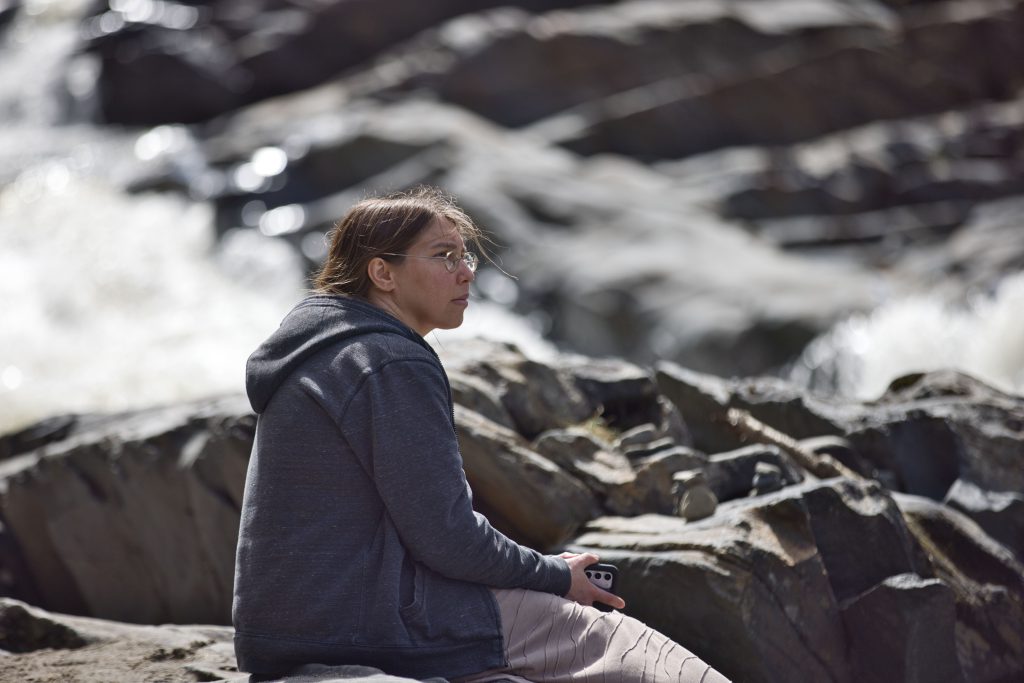 woman sits next to Willoughby Falls Orleans Vermont