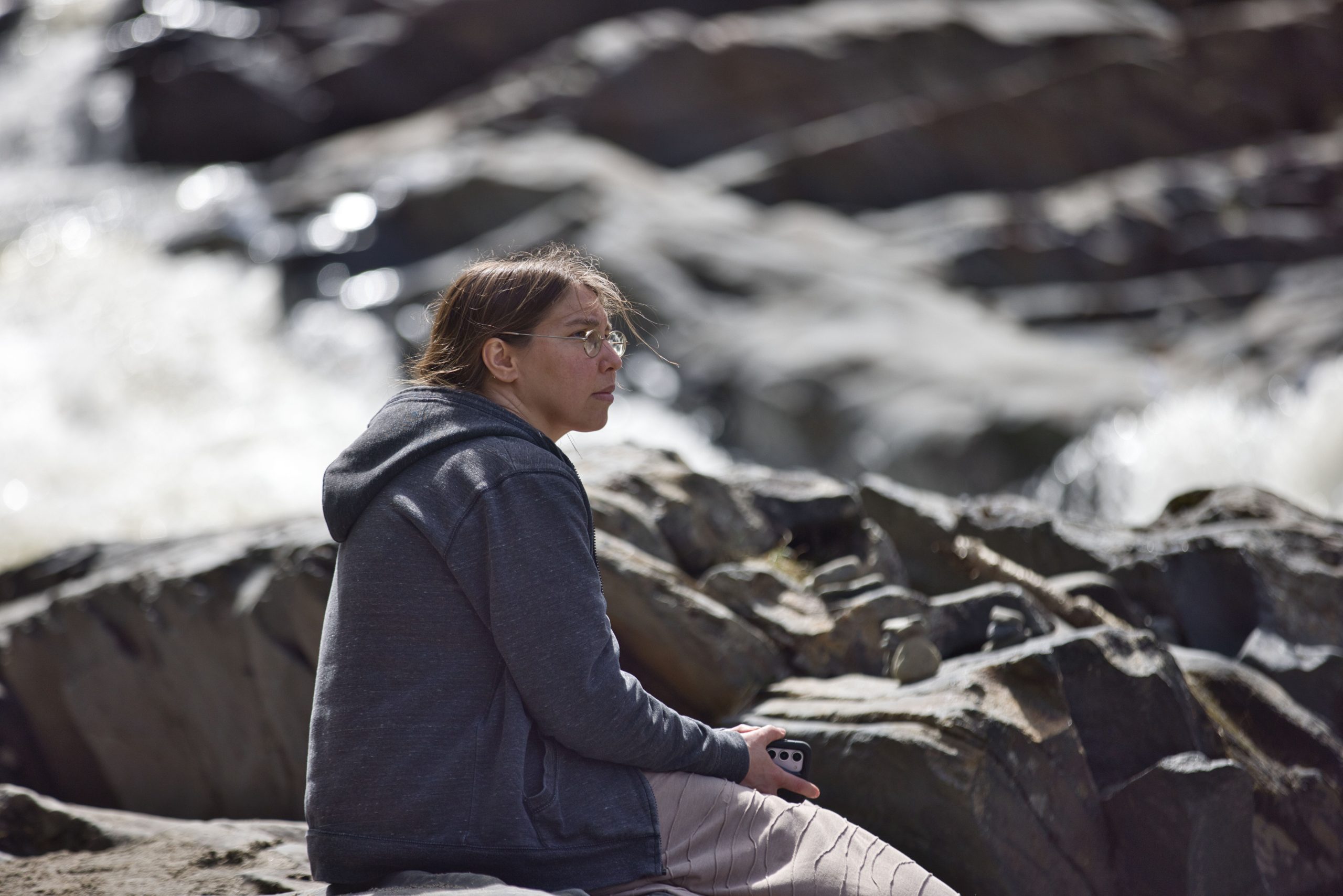 woman sits next to Willoughby Falls Orleans Vermont
