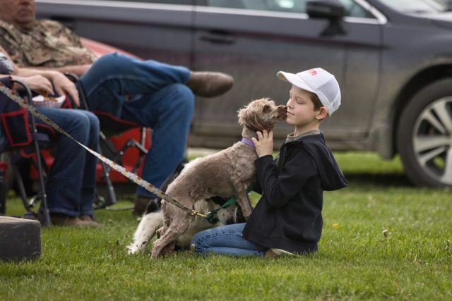 poll and barrels – Brady Davis of Duxbury Young boy shares an affectionate moment with a dog while watching the pole bending and barrel racing competitions at the Orleans County Fairgrounds.