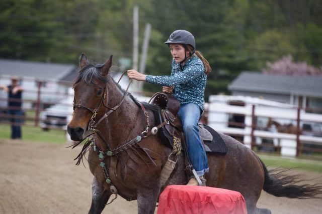 Horse and rider turn around a barrel during competition at the Orleans County Fairgrounds