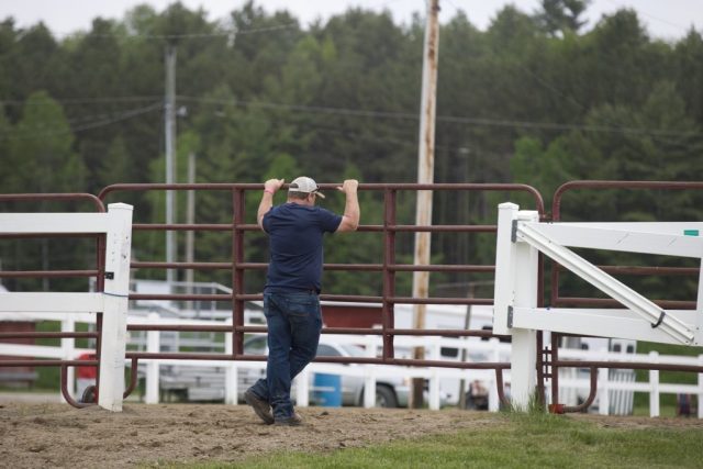 poll and barrels – gate 2 Man tends a gate during the pole bending and barrel racing competitions at the Orleans County Fairgrounds in Barton, Vermont.