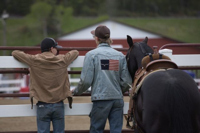 poll and barrels – watching Two men stand with a saddled horse along the arena fence during equestrian events at the Orleans County Fairgrounds in Barton, Vermont.