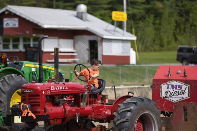 tractor pull – Rocky Vance – 1st grader Young boy sits behind the wheel of a vintage Farmall tractor during Memorial Day Tractor Pulls at the Orleans County Fairgrounds in Barton, Vermont.