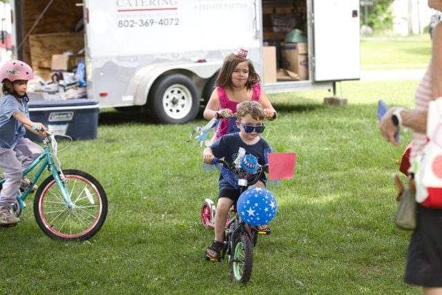 4G0A3516 Children ride a decorated bicycle and scooter across the Danville Green during the patriotic children’s parade at the Danville Farmers Market in Danville, Vermont.